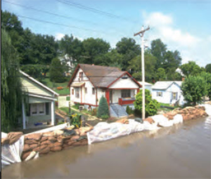 A street with sand bags in front of the homes holding back a river of water that was once the road
